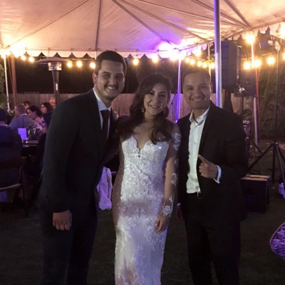 Bride, groom and the DJ under a string-lit tent at night