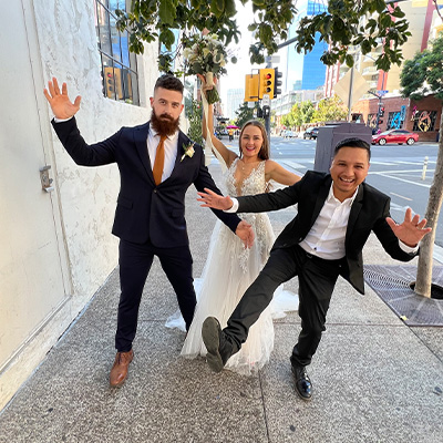 The DJ and the newlyweds jumping on a downtown sidewalk