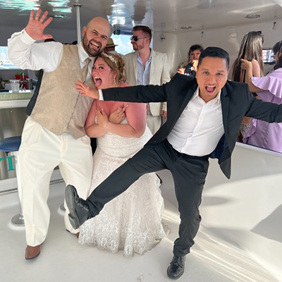 The DJ high-kicking with newlyweds in a white ballroom