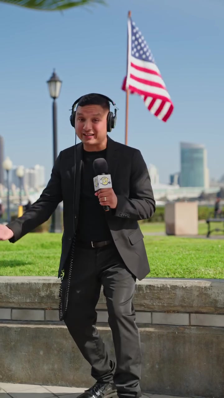 The DJ in headphones holding a branded microphone on the San Diego waterfront
