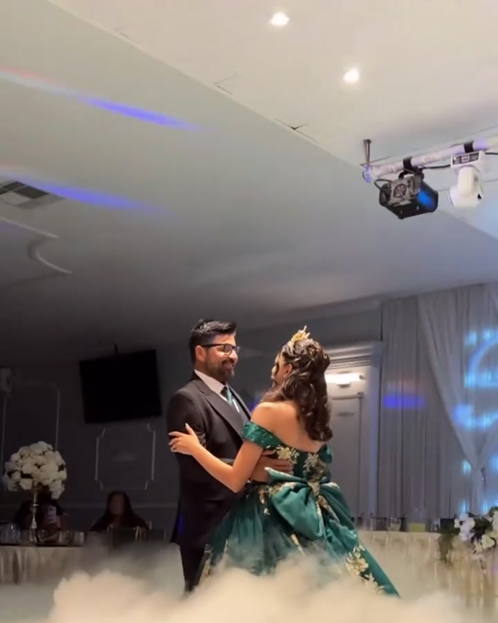 Quinceañera and her father dancing on a cloud of low fog under monogram lighting